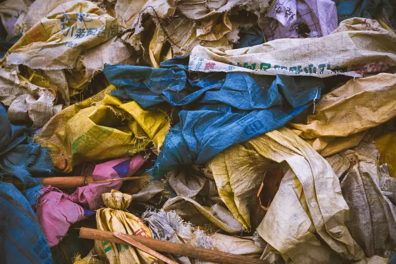 Una mezcla llena de vida de bolsas de tela desechadas en una pila de reciclaje, que pone de manifiesto la importancia de la gestión de residuos.